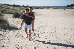 Couple doing a piggyback ride on a sandy beach