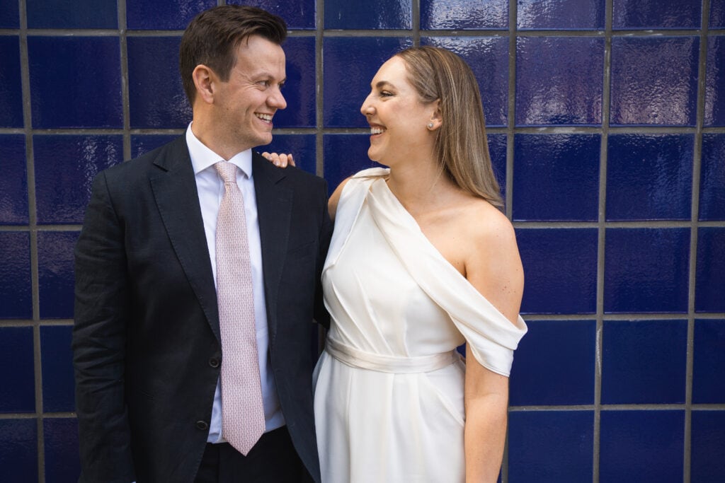 Couple smiling at each other in front of tiled background
