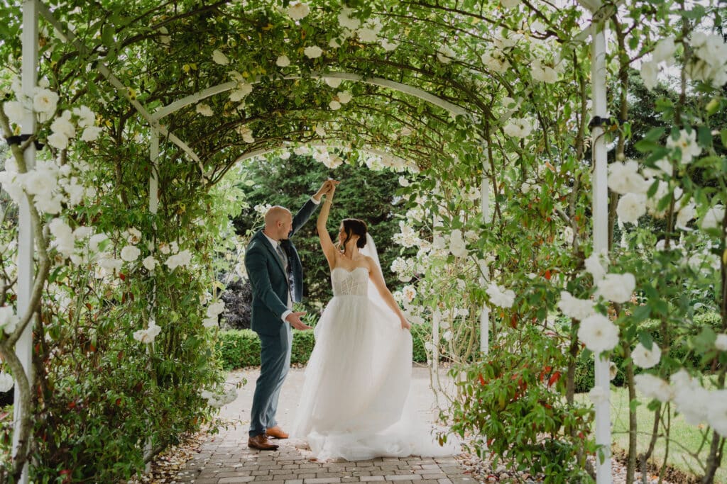a bride and groom dancing in a flower archway at The Ferry House in Kent