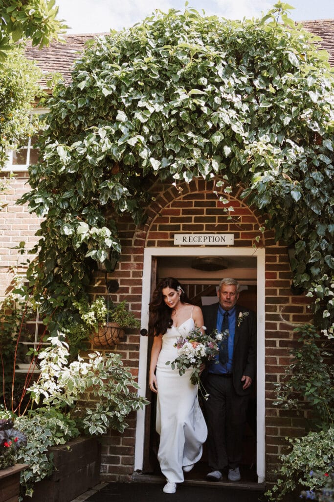 bride and father walking out of the door of a historic manor